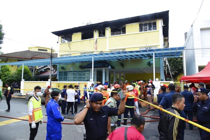 Police and rescue personnel work at an Islamic religious school cordoned off after a fire Thursday on the outskirts of Kuala Lumpur. Photo: Associated Press