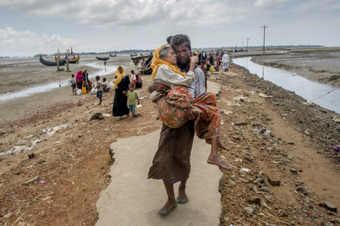 FILE - In this Sept. 16, 2017, file photo, Abdul Kareem, a Rohingya Muslim man, carries his mother, Alima Khatoon, to a refugee camp after crossing over from Myanmar into Bangladesh, at Teknaf, Bangladesh. Photo: Dar Yasin / Associated Press