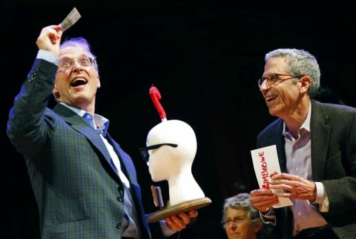 James Heathcote, at left, reacts to receiving a worthless Zimbabwean cash prize along with the Ig Nobel Anatomy Prize from Nobel laureate Eric Maskin (economics, 2007) on Thursday at Harvard University in Cambridge, Massachusetts. Photo: Michael Dwyer / Associated Press