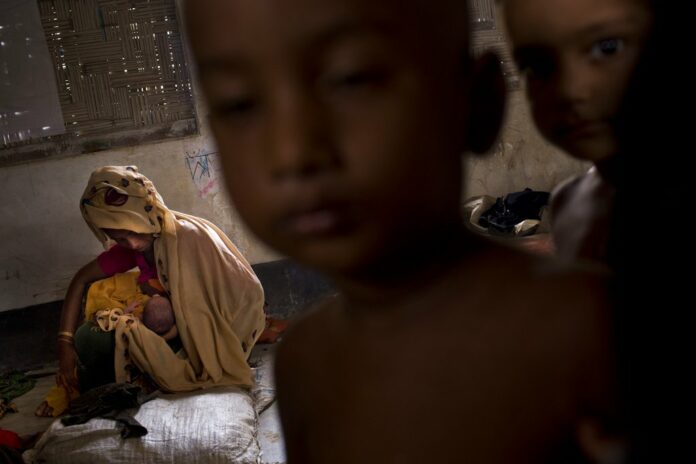 Zahida Begum, a 25-year-old Rohingya Muslim woman, on Thursday cradles her few-hours-old son who she gave birth to alone in the toilet outside the room, at Kutupalong refugee camp, Bangladesh. Photo: Bernat Armangue / Associated Press