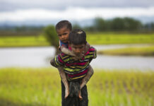 40 Years After Genocide Came Knocking, Hate is the New Apathy for Some Thais A young Rohingya Muslim boy from Myanmar carries a child on his back on and walks through rice fields after crossing over to the Bangladesh side of the border in 2017 near Cox's Bazar's Teknaf area in Bangladesh. Photo: Bernat Armangue / Associated Press