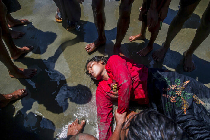 A Rohingya Muslim woman, who crossed over from Myanmar into Bangladesh, lies unconscious on the shore of the Bay of Bangal in 2017 after the boat she was traveling in capsized at Shah Porir Dwip, Bangladesh. Photo: Dar Yasin / Associated Press