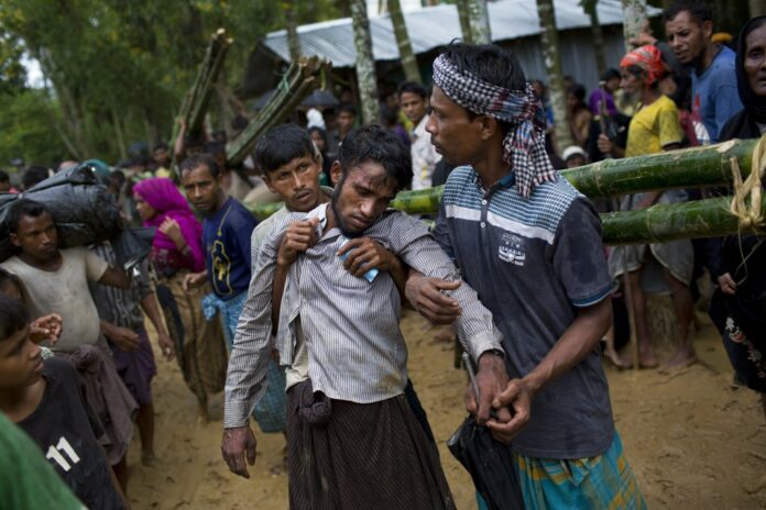 Kifawet Ullah is helped by other newly arrived Rohingya after he collapsed while waiting to have his token validated in order to collect a bag of rice distributed by aid agencies in Kutupalong, Bangladesh on Saturday. Photo: Bernat Armangue / Associated Press