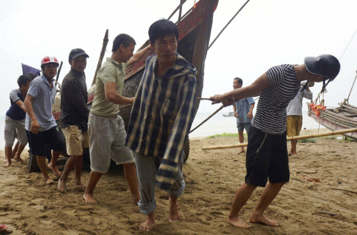Vietnamese villagers move a fishing boat on shore Thursday in northern Thanh Hoa province. Photo: Trinh Duy Hung / Vietnam News Agency