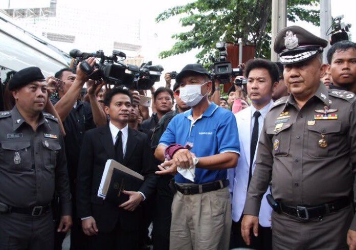 Bombing suspect Wattana Pumares is flanked by police in a