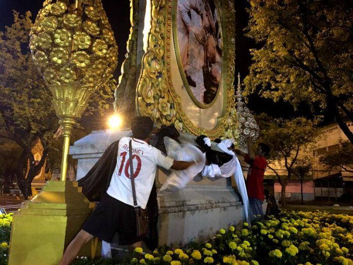 City Hall staff remove black-and-white decorations early Monday morning from an image of King Bhumibol on Ratchadamnoen Avenue in Bangkok.