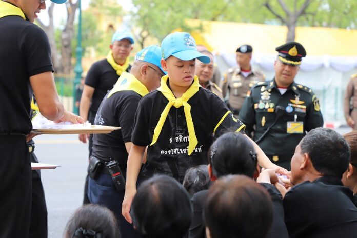 Prince Dipangkorn Rasmijoti, a son of King Vajiralongkorn, distributes inhalers Wednesday to members of the public waiting to watch the royal cremation in Bangkok.