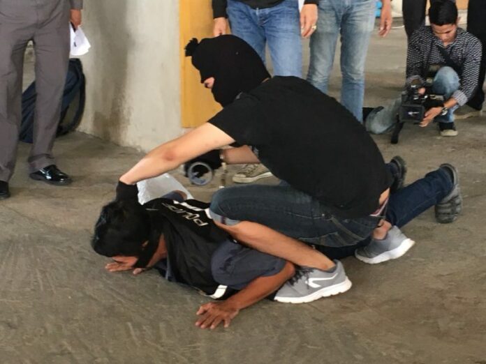 Perpetrators lead police through a “crime re-enactment” Friday morning in the parking lot at the Ratchada Pavilion condominium.