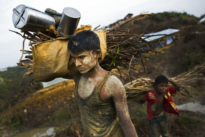 Rohingya refugee Zannet Ullah, 20, covered in mud after installing latrines in the camp, walks back to his new shelter Sunday in Kutupalong extension camp, in Cox's Bazar, Bangladesh. Photo: Bernat Armangue / Associated Press