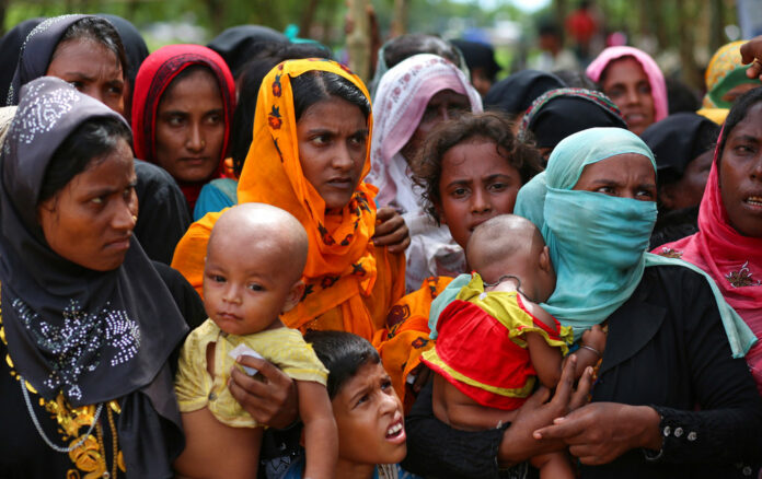 Rohingya women carry children and wait for food handouts in 2017 at Thangkhali refugee camp in Cox's Bazar, Bangladesh. Photo: Zakir Hossain Chowdhury / Associated Press