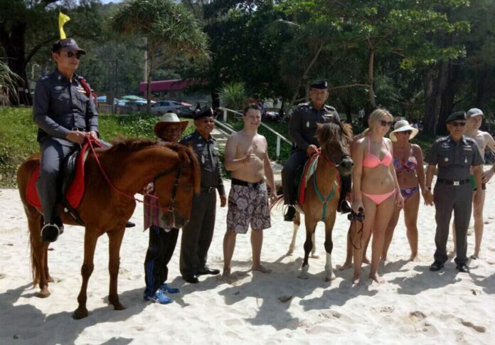 Horseback patrol police pose for photos with tourists on Surin Beach in Phuket province Dec. 9, 2016