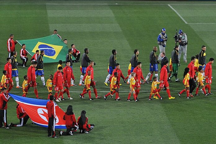 The North Korean football team walk out alongside the Brazilian football team during the 2010 FIFA World Cup in South Africa. Photo: Marcello Casal Jr/ABr / Wikimedia Commons