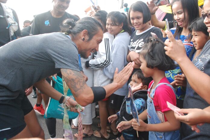 Toon Bodyslam gives a high-five to a child Saturday in Prachuap Khiri Khan province