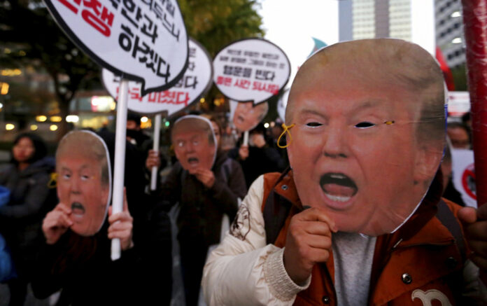 Protesters wearing masks of U.S. President Donald Trump march toward the US Embassy at a rally Saturday to oppose his planned visit in Seoul, South Korea. The signs read 'Stop the War.' Photo: Ahn Young-joon / Associated Press