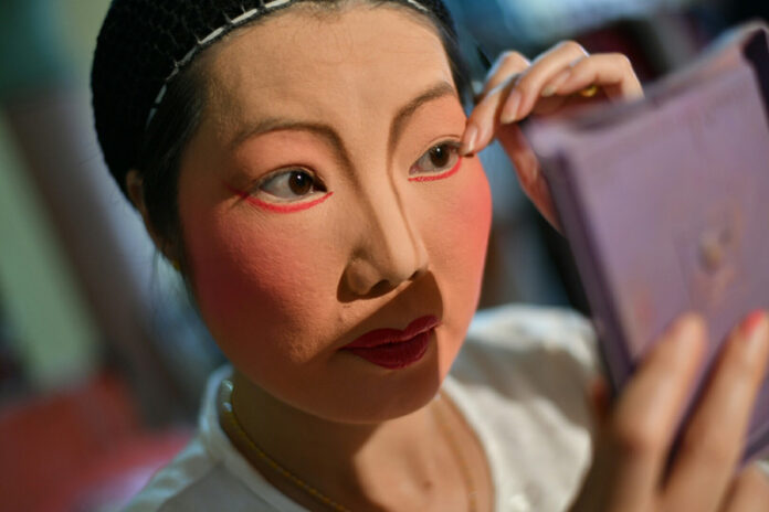 A ngiew actress from the Sai Yong Hong troupe puts on her stage makeup.