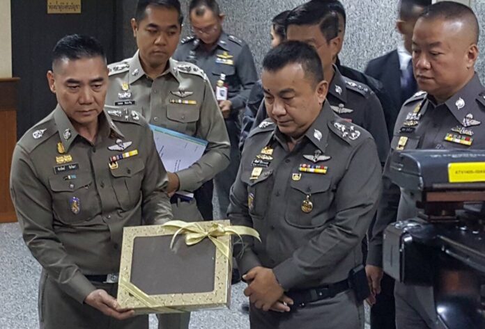 Police commissioner Chakthip Chaijinda shows reporters Friday a sample of a new khaki shade to be implemented in police uniform nationwide.