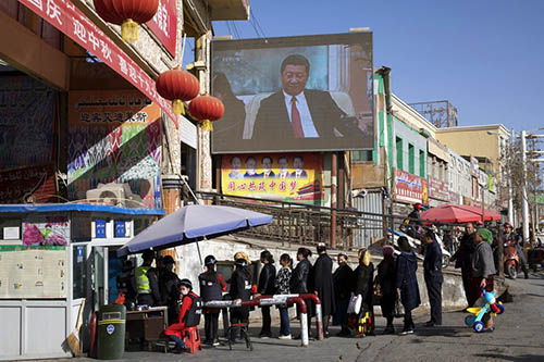 Residents walk through a security checkpoint into the Hotan Bazaar where a screen shows Chinese President Xi Jinping in Hotan in western China's Xinjiang region. Photo: Ng Han Guan / Associated Press