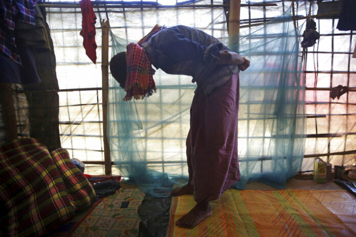 In this Monday, Nov. 27, 2017, photo, Mohamed Yaha, 18, demonstrates to The Associated Press in his tent in Jamtoli refugee camp in Bangladesh, what he saw when soldiers bound the hands of dozens of men behind their backs with nylon rope and blindfolded them with scarves taken from the women when they massacred his village Maung Nu, in Myanmar's Rakhine State. (AP Photo/Wong Maye-E)