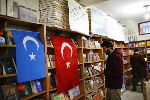 A man reads a book on Dec. 14 in a bookstore where flags which represents Turkey and 'East Turkistan,' the name Uighurs who oppose Chinese rule call their homeland, are hung in Istanbul's Zeytinburnu neighborhood. Photo: Emrah Gurel / Associated Press