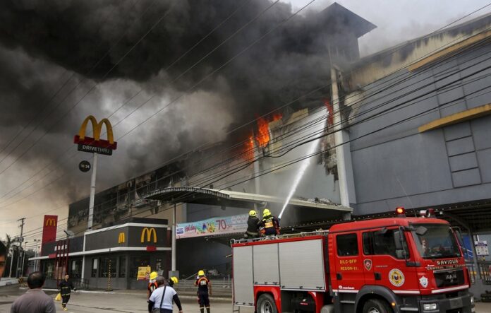 Firemen battle a fire that rages at a shopping mall, Saturday in Davao city, southern Philippines. Photo: Manman Dejeto / Associated Press
