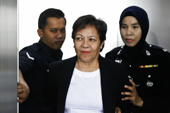 Australian Maria Elvira Pinto Exposto, at center, is escorted by a police officer at a court hearing Wednesday at Shah Alam High Court in Shah Alam, Malaysia. Photo: Sadiq Asyraf / Associated Press