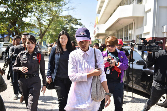 Sukanya Tanyakan, wearing cap, and Supicha Tankyakan, in black, walk to a police station in Nakhon Nayok province Tuesday afternoon.