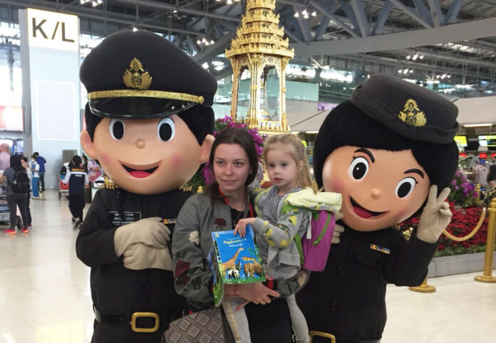 A family takes a photo with Immigration Police mascots Temjai Haiborigan and Yimyaem Jaemsai on Monday at Suvarnabhumi Airport. Photo: Immigration Police Division 2