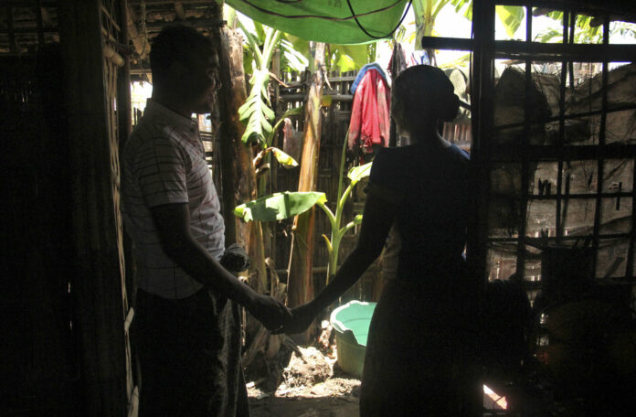 In this July 16, 2017, photo, Setara, right, holds her husband Mohammad's hand in Thetkabyin village camp, near Sittwe, Myanmar. Photo: Esther Htusan / Associated Press