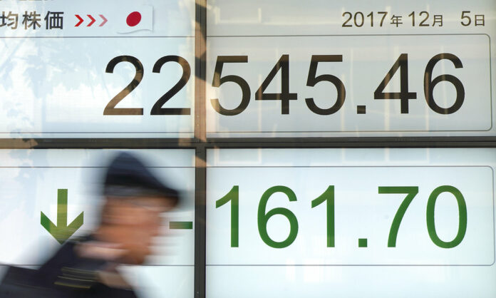 A man walks past an electronic stock board showing Japan's Nikkei 225 index at a securities firm in Tokyo on Dec. 5, 2017. Photo: Eugene Hoshiko / Associated Press