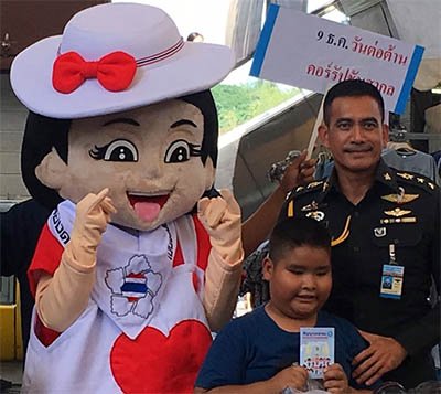 Army mascot 'Nong Kiew Koy' menaces/cheers a young boy.