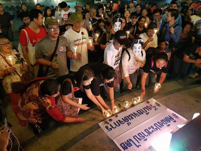 Protesters light candles Sunday at Bangkok's Democracy Monument next to posters which reading #ThinkingOfDemocracy and #DespisedDictatoship. Photo: Noppakaw Kongsuwan