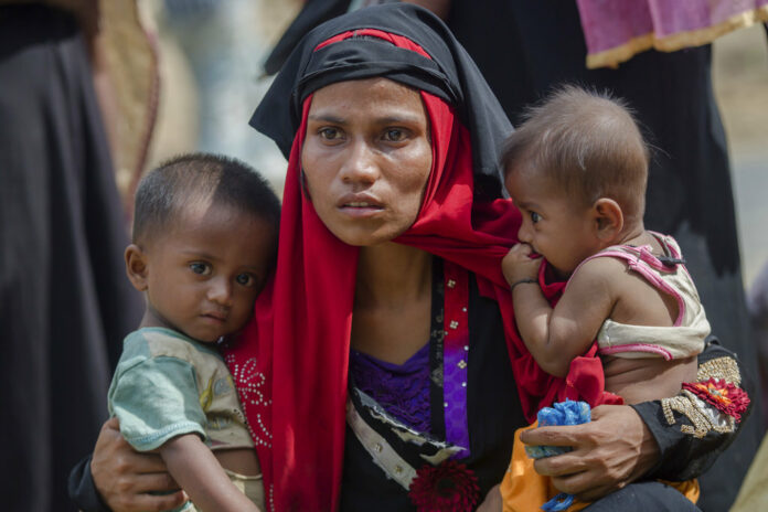 Rohingya Muslim woman, Rukaya Begum, who crossed over from Myanmar into Bangladesh, holds her son Mahbubur Rehman, at left, and her daughter Rehana Bibi, on Oct. 22, 2017, after the government moved them to newly allocated refugee camp areas, near Kutupalong, Bangladesh. Photo: Dar Yasin / Associated Press