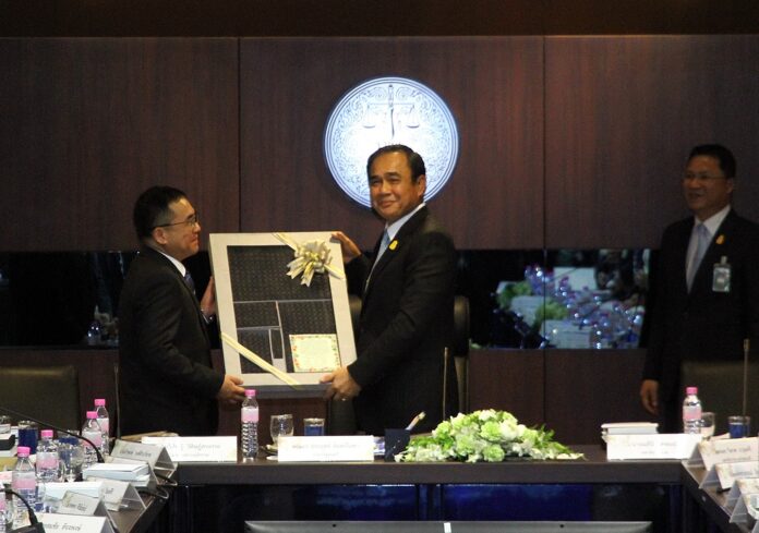 Junta chairman Prayuth Chan-ocha receives a present from an official Friday at Ministry of Justice – after making sure it cost less than 3,000 baht