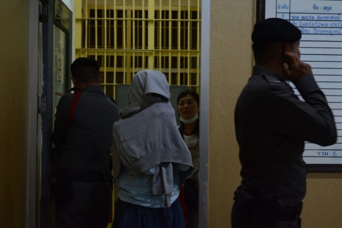 Sasithorn Wirathepsuporn covers herself Wednesday as police escort to the court