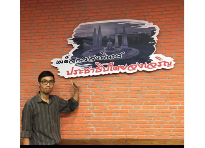In a photo which accompanied his Monday Facebook post, Activist Piyarat Chongthep points at a sign reading