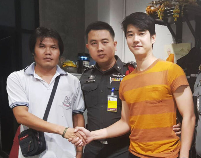 Udon Sutthison, left, shakes hands with Mario Maurer Monday at Phaya Thai Police Station.