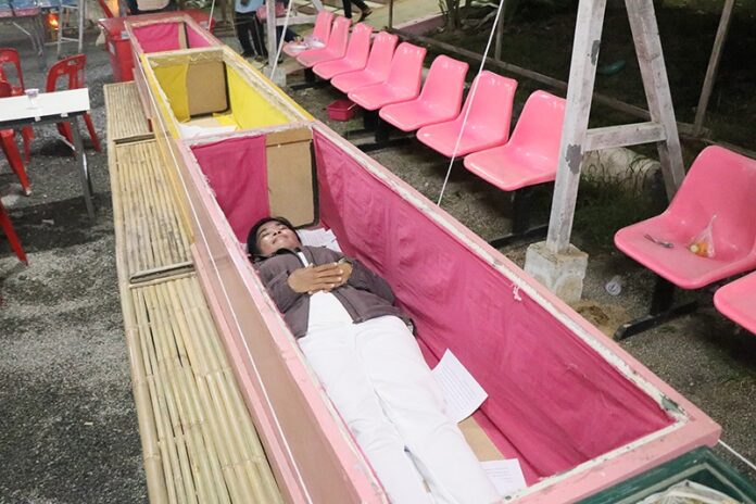A believer on Tuesday in Suphan Buri lies in a coffin to wish for good luck.