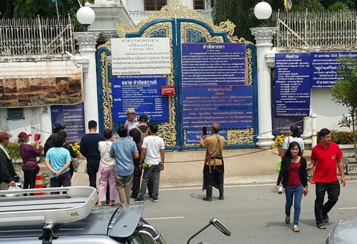 Curious onlookers gather in front of the Saengyotrakarn mansion on Saturday
