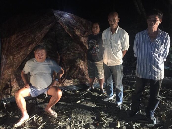 Premchai Karnasuta, far left, sits in the campsite where he was found on Feb. 5 with the remains of a leopard, panther and other wildlife in the Thungyai Naresuan Wildlife Sanctuary in Kanchanaburi province.