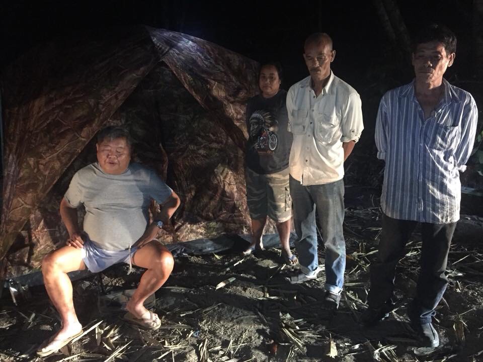 Premchai Karnasuta, far left, on Feb. 5 sits in the campsite where he was found with the remains of a leopard, panther and other wildlife in the Thungyai Naresuan Wildlife Sanctuary in Kanchanaburi province.