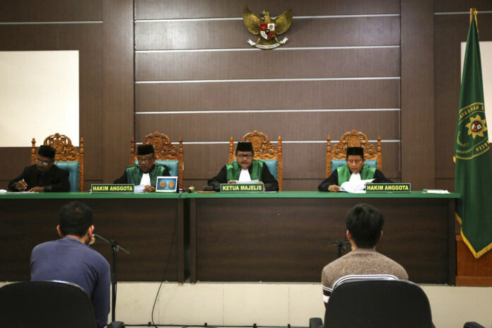 Two men accused of having gay sex sit on the defendants' chairs in May during their trial at the Shariah Court in Banda Aceh, Indonesia. Photo: Heri Juanda / Associated Press