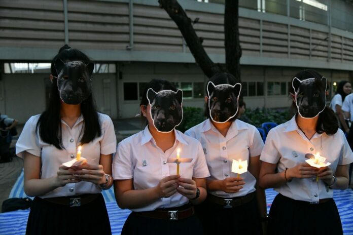 Chulalongkorn students on Tuesday evening wear black panther masks and hold candles to mourn killed animals at the Thungyai Naresuan Wildlife Sanctuary.