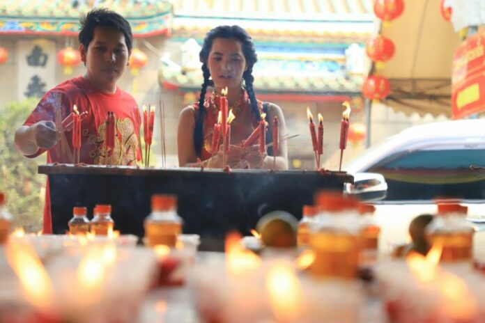 Two people burn incense Thursday at Wat Mangkon in Chinatown.