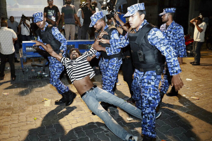 Maldivian police officers on Feb. 2 detain an opposition protester demanding the release of political prisoners during a protest in Male, Maldives. Photo: Mohamed Sharuhaan / Associated Press