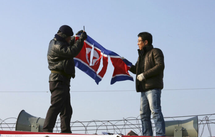 A South Korean protester tear a North Korean flag with a knife, during a rally against a visit of Kim Yong Chol, vice chairman of North Korea's ruling Workers' Party Central Committee, near the Unification bridge in Paju, South Korea, on Sunday. Photo: Ahn Young-joon / Associated Press