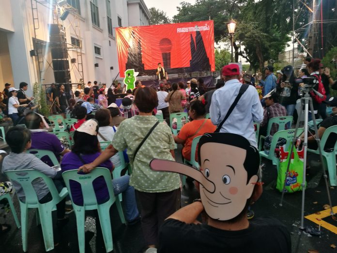 A Prayuth-as-Pinocchio mask is worn by an attendee of a Saturday pro-democracy rally at Thammasat University.