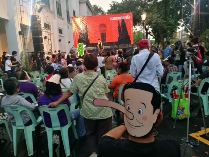 A Prayuth-as-Pinocchio mask is worn by an attendee of a Saturday pro-democracy rally at Thammasat University.