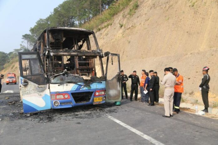 Officials on Friday inspect the scene of the fatal bus fire in Tak province