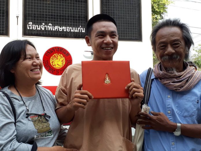 Jatupat ‘Pai Dao Din’ Boonpattaraksa, holding his law degree, poses for a photo with his parents on March 23 outside a court in Khon Kaen province