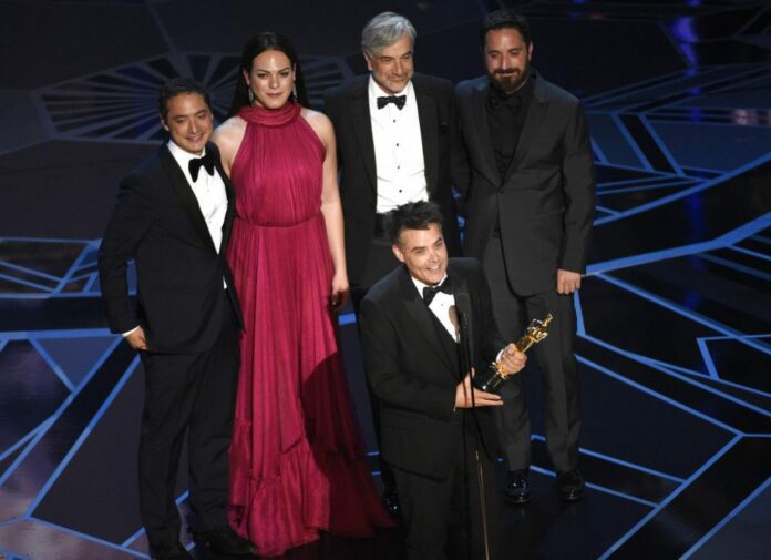 Sebastian Lelio, foreground center, and Nicolas Saavedra, from back left, Daniela Vega, Alejandro Goic, and Pablo Larrain accept the award for best foreign language film for